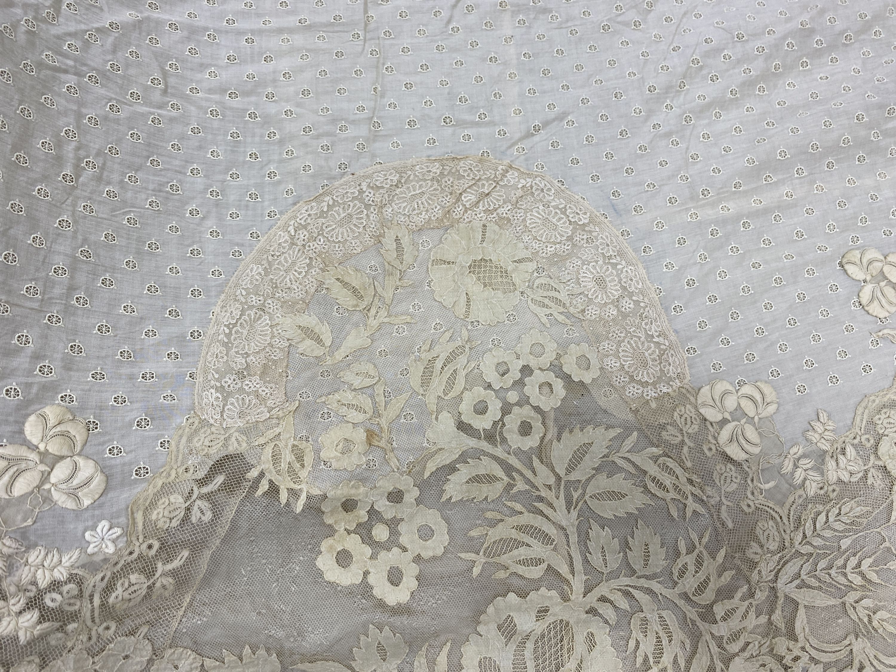 An Edwardian hand made lace bedspread. Hand sewn using finely spun lawn, decorated with Carrickmacross and white work embroidery, edged in bobbin lace. Possibly made as part of a trousseau.